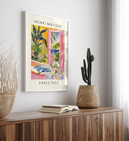Tropical framed artwork of a whale lounging in a tub with open pink doors and a lush ocean setting, Matisse-inspired.